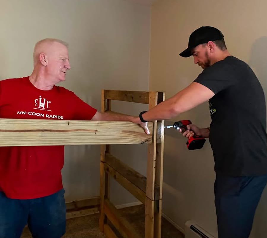 Andrew Malm assembling a bunk bed with a Sleep in Heavenly Peace volunteer