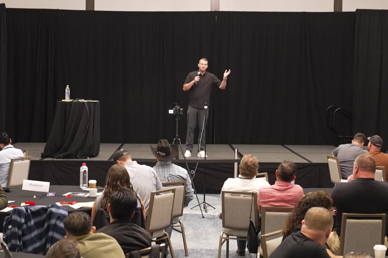Andrew Malm on stage in front of a full room of investors